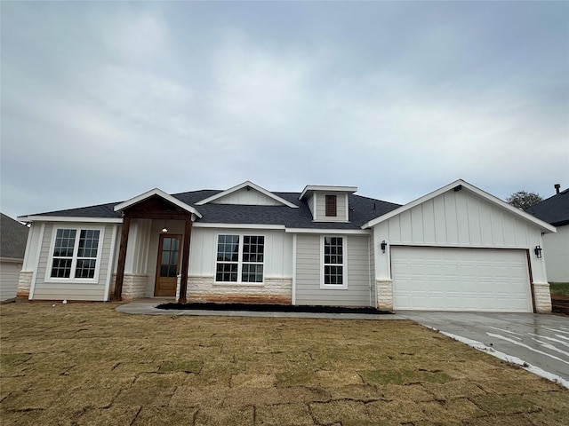 view of front facade featuring a front lawn, driveway, stone siding, board and batten siding, and a garage