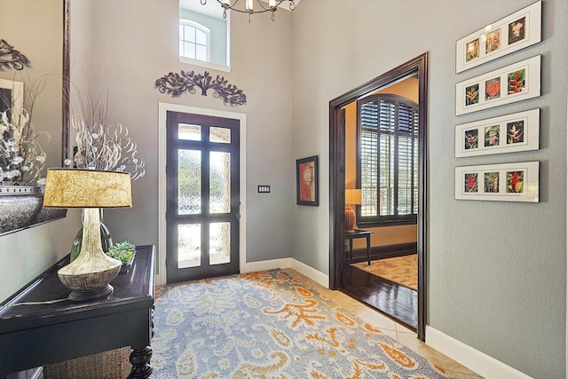 foyer featuring tile patterned floors, a notable chandelier, french doors, and baseboards