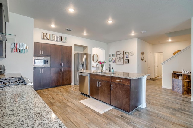 kitchen featuring visible vents, light wood-style flooring, a sink, dark brown cabinetry, and appliances with stainless steel finishes