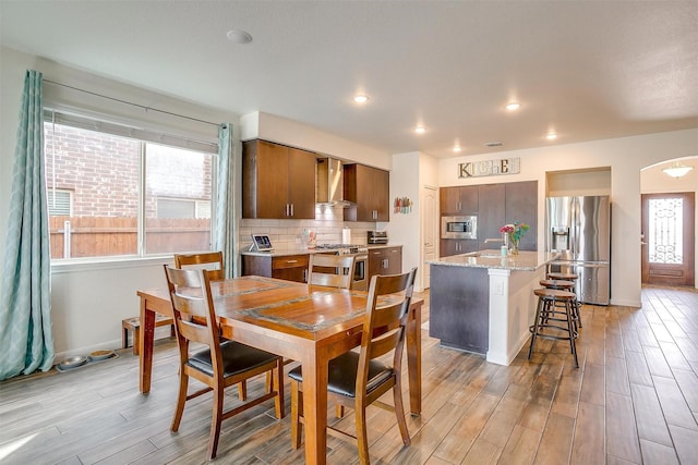 dining space with recessed lighting, baseboards, light wood-style floors, and arched walkways