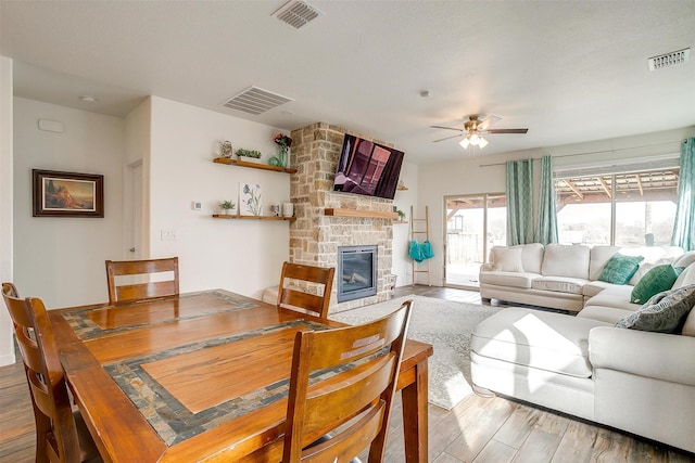 living room featuring visible vents, a fireplace, a ceiling fan, and wood finished floors