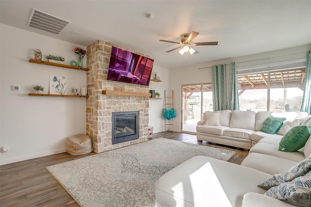 living area featuring visible vents, baseboards, a fireplace, wood finished floors, and a ceiling fan