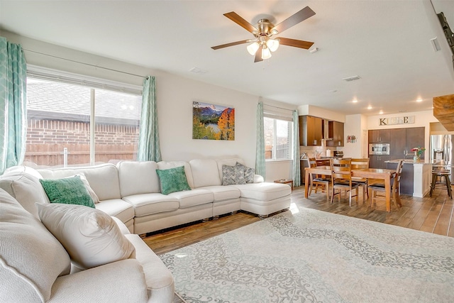 living area with light wood finished floors, visible vents, and ceiling fan