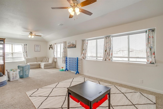 carpeted living area with a wealth of natural light, visible vents, baseboards, and a ceiling fan