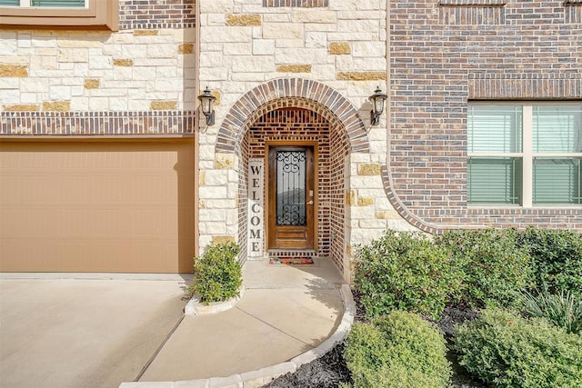 view of exterior entry featuring brick siding, stone siding, and a garage