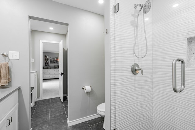 bathroom with vanity, baseboards, tiled shower, tile patterned flooring, and toilet