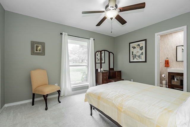 bedroom featuring connected bathroom, a ceiling fan, baseboards, and light carpet