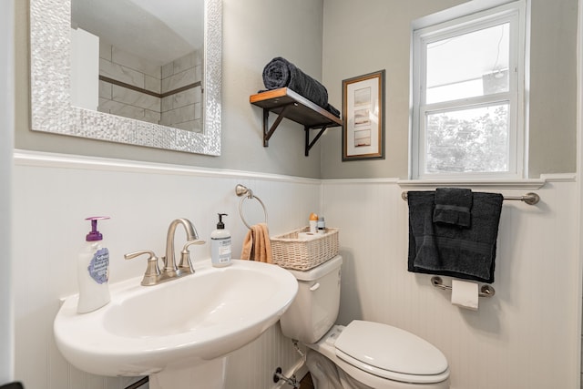 bathroom featuring toilet, wainscoting, and a sink