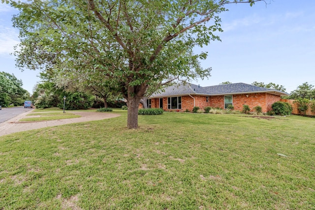 view of front facade featuring brick siding, a front yard, and fence