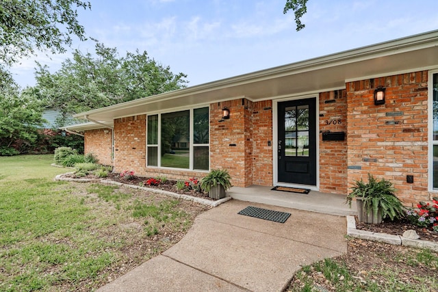 doorway to property with a yard and brick siding