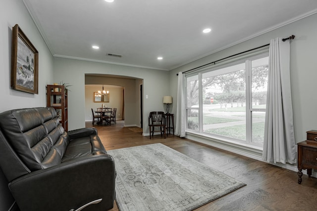 living area with visible vents, crown molding, recessed lighting, wood finished floors, and arched walkways