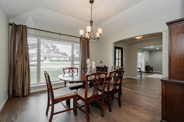 dining space featuring arched walkways, baseboards, dark wood-type flooring, and lofted ceiling