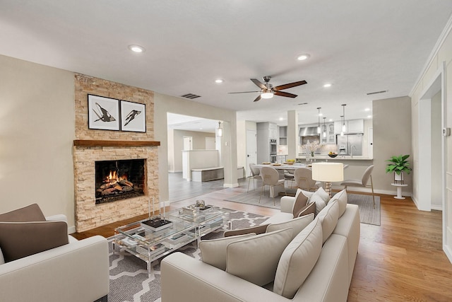 living area featuring light wood finished floors, baseboards, recessed lighting, a fireplace, and a ceiling fan