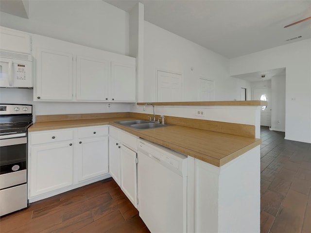 kitchen featuring white appliances, visible vents, a peninsula, a sink, and white cabinets