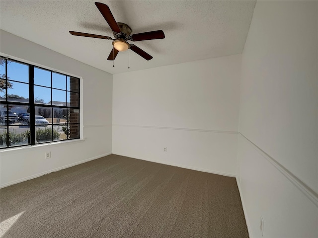 spare room with ceiling fan, baseboards, dark colored carpet, and a textured ceiling