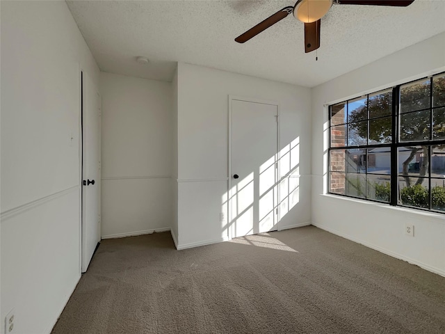 spare room featuring ceiling fan, carpet, baseboards, and a textured ceiling