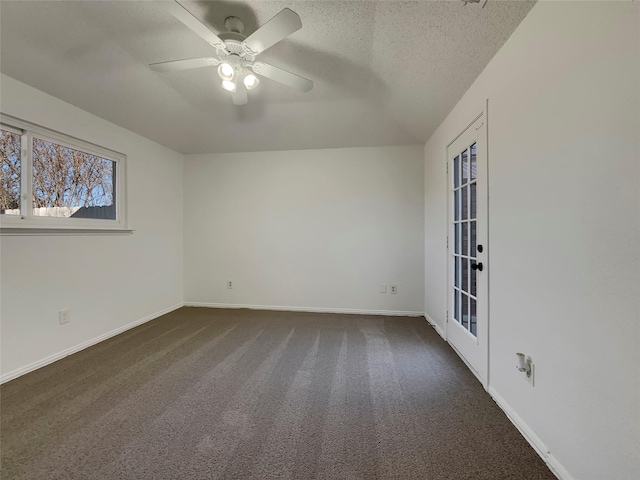 empty room with dark carpet, a textured ceiling, baseboards, and ceiling fan