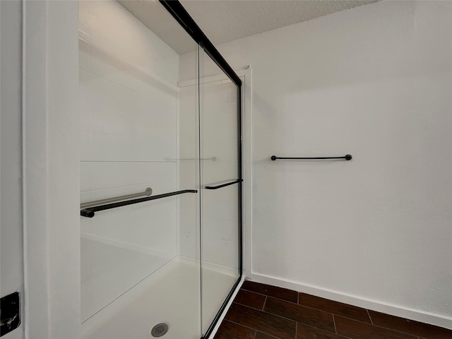 full bathroom featuring a shower stall, a textured ceiling, baseboards, and wood tiled floor