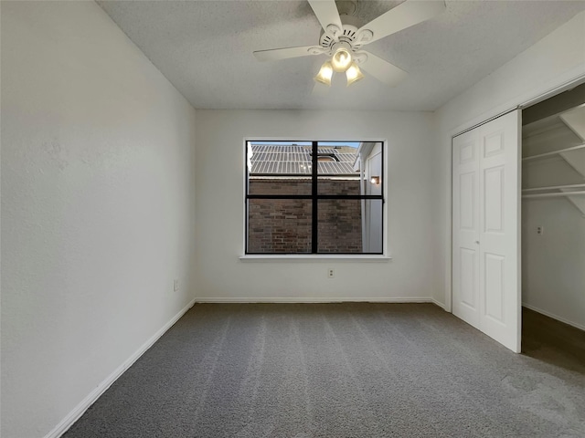 unfurnished bedroom featuring a textured ceiling, a closet, carpet flooring, baseboards, and ceiling fan