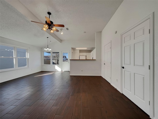 unfurnished living room featuring visible vents, dark wood-type flooring, lofted ceiling with beams, ceiling fan with notable chandelier, and a textured ceiling