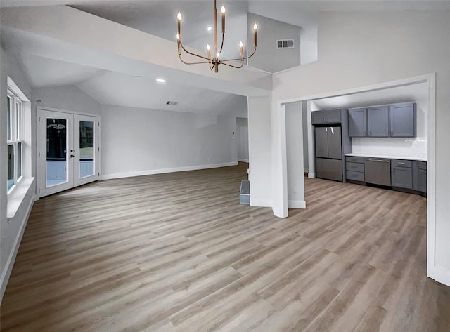 unfurnished living room with french doors, light wood finished floors, baseboards, and vaulted ceiling