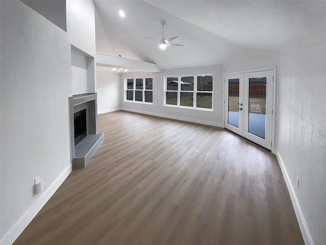 unfurnished living room featuring a fireplace with raised hearth, ceiling fan with notable chandelier, baseboards, and wood finished floors