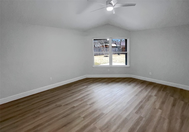 empty room with lofted ceiling, wood finished floors, baseboards, and ceiling fan