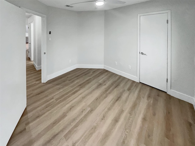 empty room with baseboards, wood finished floors, visible vents, and ceiling fan