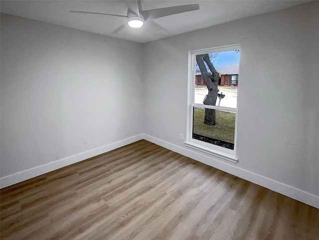 empty room featuring a ceiling fan, wood finished floors, and baseboards