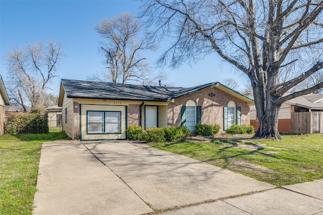 view of front of home featuring brick siding, concrete driveway, a front lawn, and fence