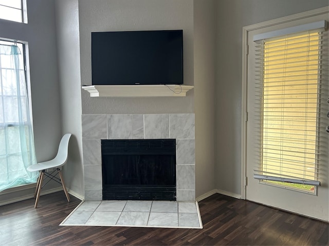 details with baseboards, wood finished floors, and a tiled fireplace