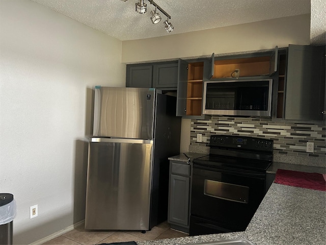 kitchen with decorative backsplash, light tile patterned flooring, appliances with stainless steel finishes, and a textured ceiling