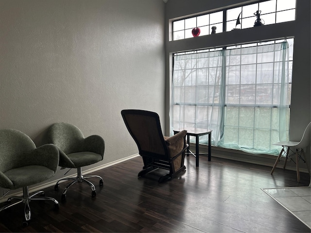 sitting room with a textured wall, baseboards, and wood finished floors