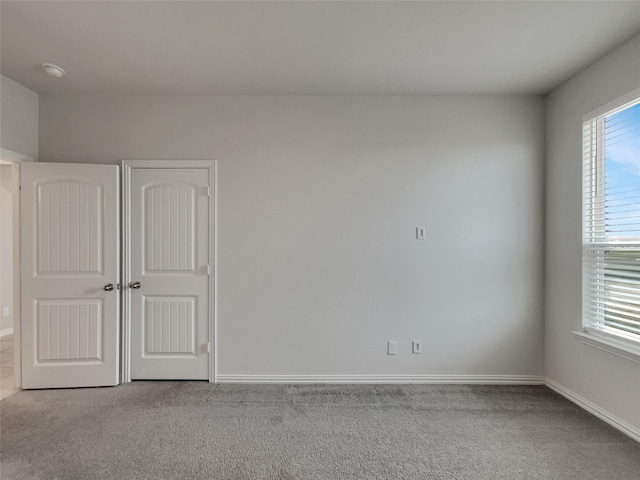 empty room featuring carpet flooring, plenty of natural light, and baseboards