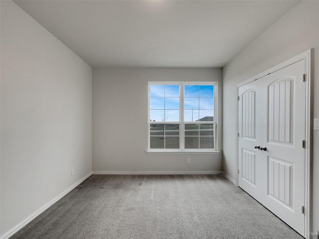 unfurnished bedroom with baseboards, carpet floors, and a closet