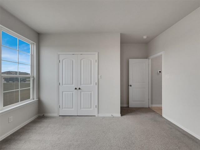 unfurnished bedroom with carpet flooring, baseboards, and a closet