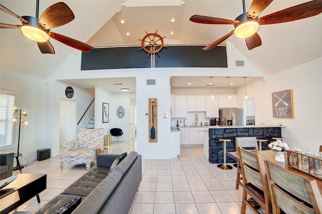 living room featuring light tile patterned floors, visible vents, a ceiling fan, and stairs