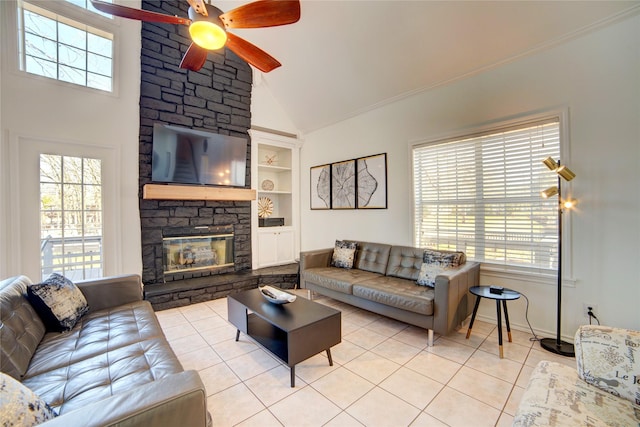 living area with built in shelves, baseboards, ceiling fan, light tile patterned floors, and a stone fireplace