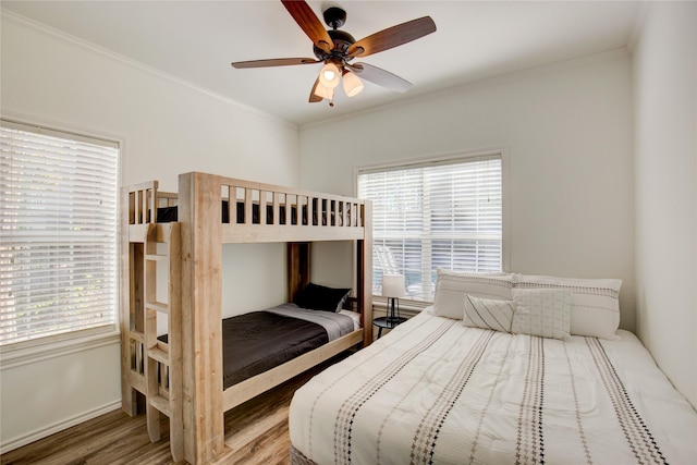 bedroom with ceiling fan, baseboards, wood finished floors, and crown molding