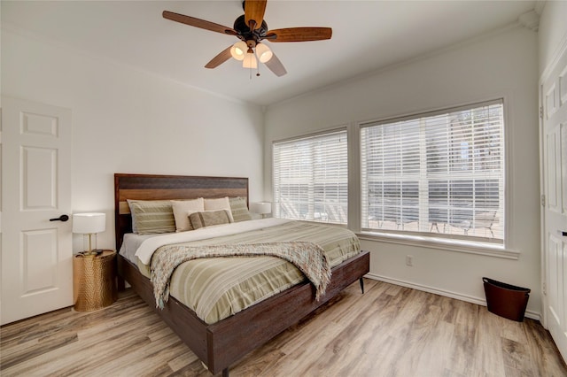 bedroom with crown molding, light wood-type flooring, and ceiling fan