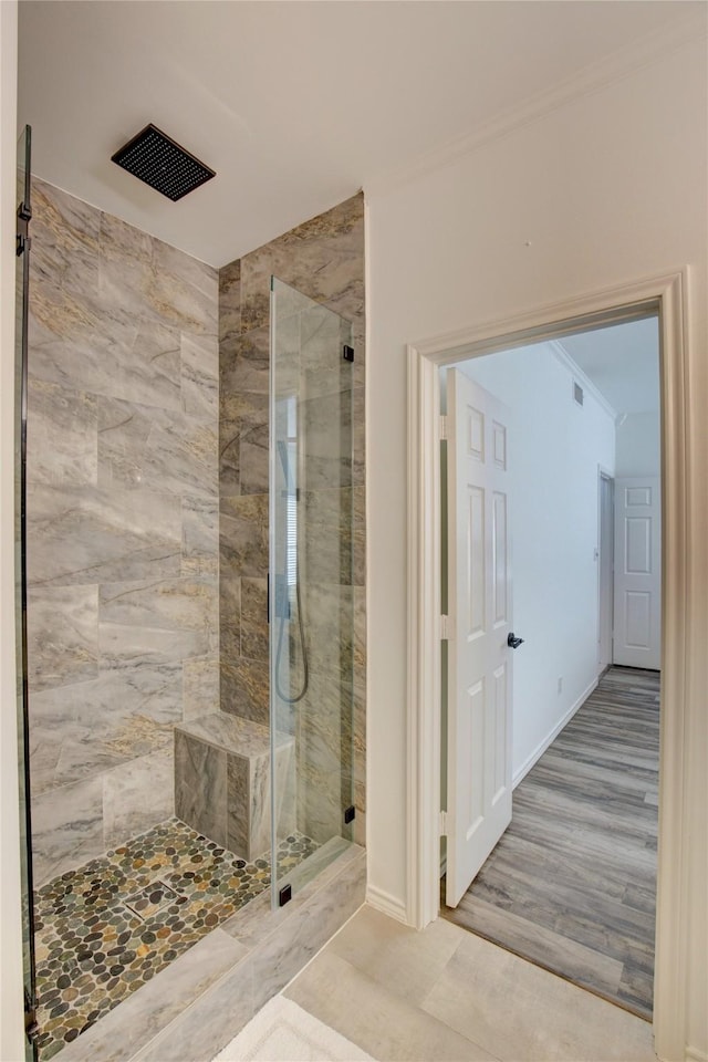 bathroom with baseboards, a shower stall, wood finished floors, and crown molding