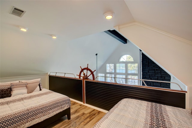 bedroom with visible vents, lofted ceiling, and wood finished floors