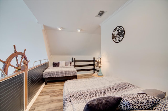 bedroom with visible vents, ornamental molding, and wood finished floors