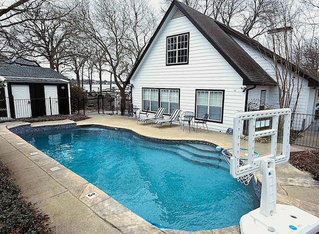 view of pool with a patio, fence, a fenced in pool, and an outdoor structure