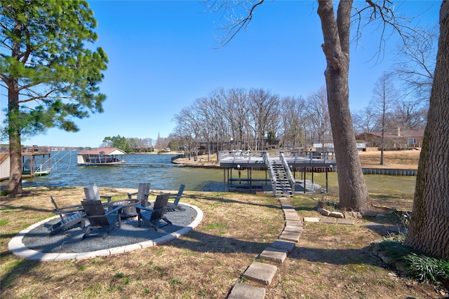 dock area with a yard, a water view, and a fire pit