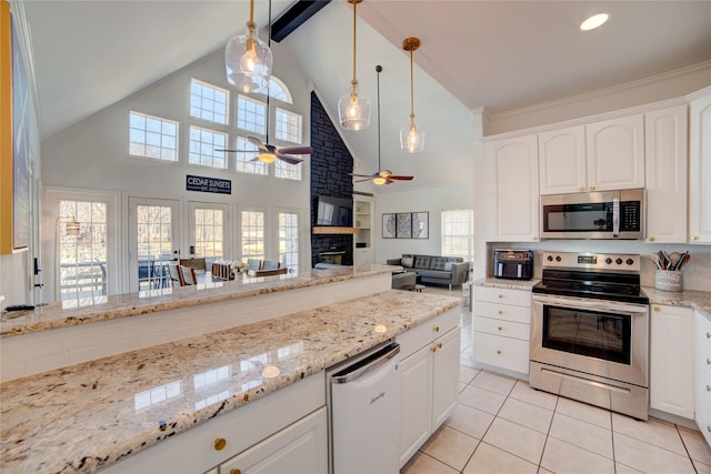 kitchen featuring light stone countertops, beam ceiling, a stone fireplace, appliances with stainless steel finishes, and light tile patterned flooring