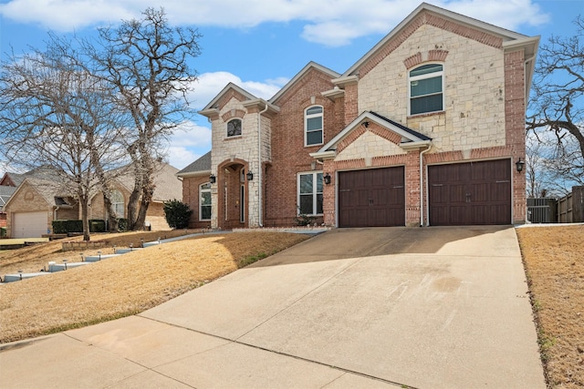 traditional-style home with brick siding, concrete driveway, an attached garage, and fence