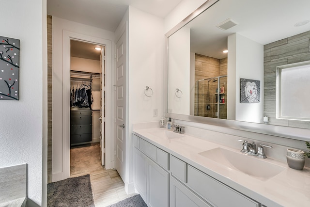 full bath with a sink, a walk in closet, visible vents, and a shower stall