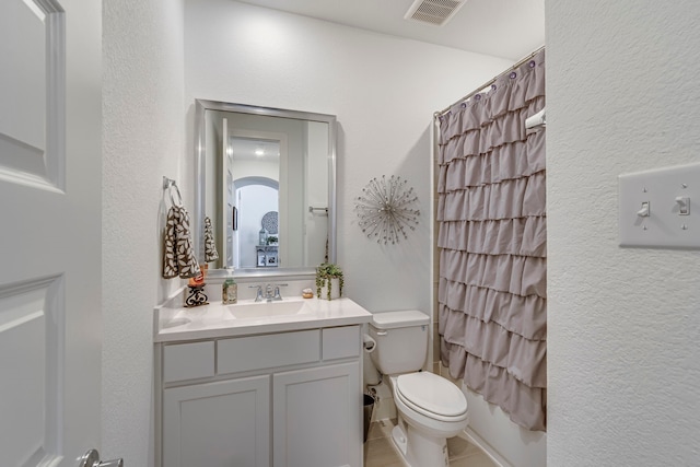 full bath featuring visible vents, curtained shower, toilet, a textured wall, and vanity