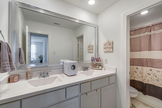 full bath with double vanity, visible vents, toilet, and a sink